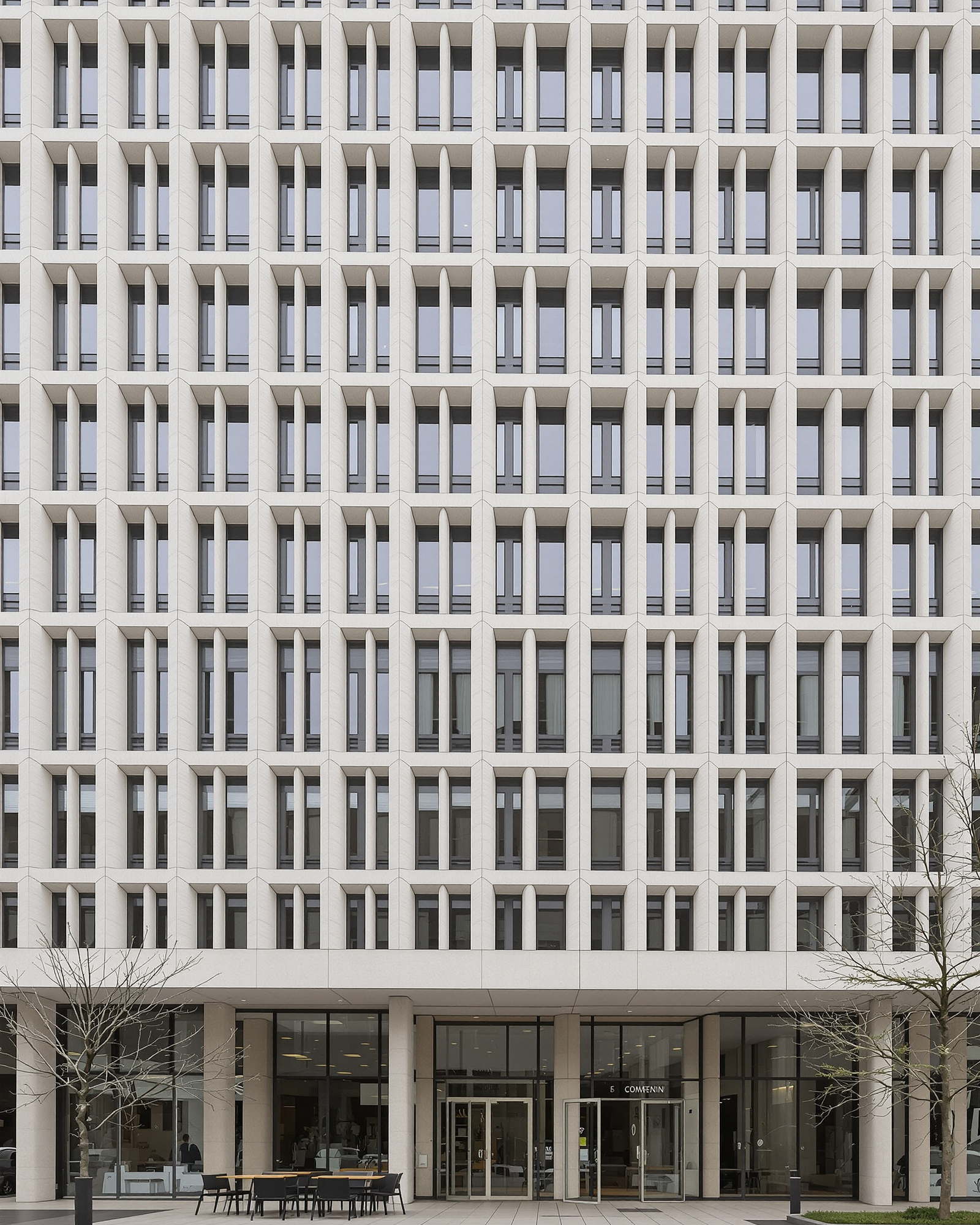 Stone and glass facade of a European university building on an overcast morning.
